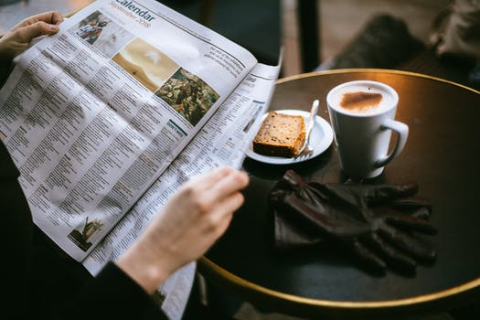 image of Man drinking coffee while reading newspaper